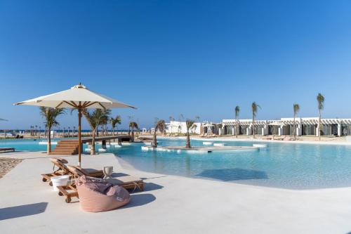 a swimming pool with lounge chairs and an umbrella at The Waterfront Cabins at D-Bay - Lemon Spaces in Zāwiyat ‘Abd al Mun‘im