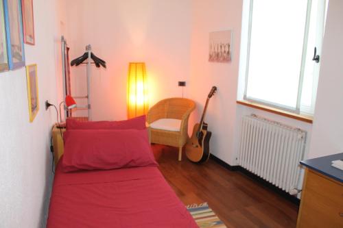 sala de estar con sofá rojo y guitarra en Piccola Torre Moltrasio, en Moltrasio