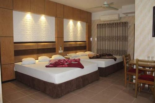 two beds in a room with a table and chairs at Saint Martin Resort in Cox's Bazar