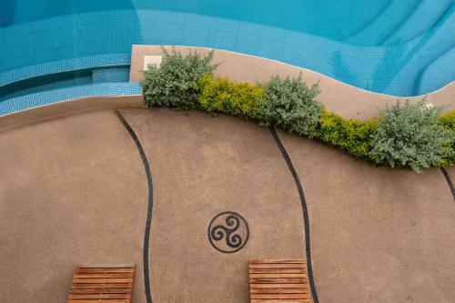 a swimming pool with two benches and plants on it at Hubun Hotel Boutique in Los Ayala