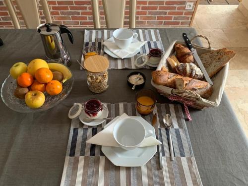 a table with a tray of bread and a bowl of fruit at La Flavignienne in Flavigny-sur-Ozerain