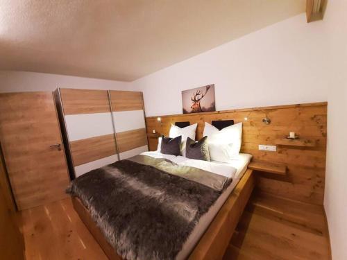 een slaapkamer met een groot bed met een houten hoofdeinde bij Hornblick Suite *NEW* Stylish 1BR + Netflix in Kirchdorf in Tirol