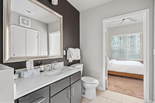 a bathroom with a sink and a toilet and a bedroom at Luxury Oasis I Mins from TX Med Center-FREEParking in Houston