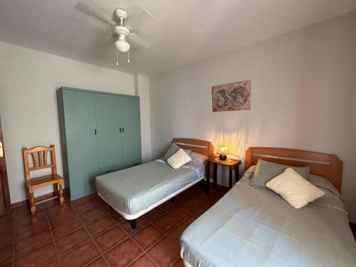 a bedroom with two beds and a chair and a cabinet at Casa Rural Cerezo in Torviscón