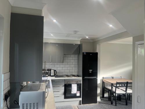 eine Küche mit einem schwarzen Kühlschrank und einem Tisch in der Unterkunft The Coral 24 Guest House MilBrook Southampton in Southampton