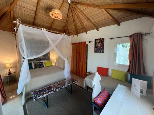 a bedroom with a bed with a mosquito net at Keur Papaye in Dinouar