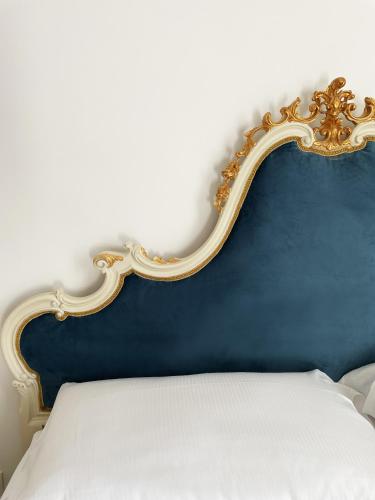 a bed with a blue and gold head board at ISOLA - Smart ApartHotel in Messina