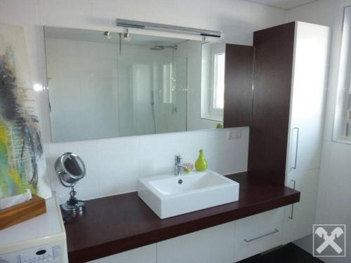 W łazience znajduje się biała umywalka i lustro. w obiekcie Stilvoll nah am See w mieście Lauterach