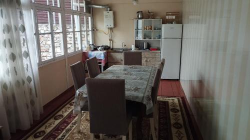 eine Küche mit einem Tisch mit Stühlen und einem Kühlschrank in der Unterkunft Ilham Mustafa Houses in Şəki