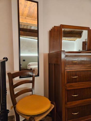 a wooden dresser with a chair and a mirror at DESTASU' Apartments in Castel del Monte
