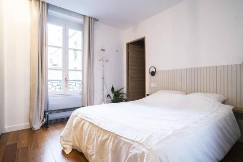 une chambre blanche avec un grand lit et une fenêtre dans l'établissement Apt design, proche Champs Elysées, à Paris
