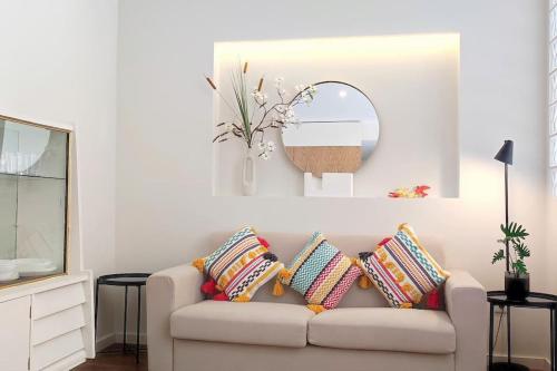 a living room with a couch with pillows and a mirror at Sweet Domus & Terrace Citycenter in Vila Nova de Famalicão