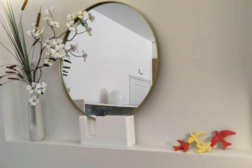 a mirror on a shelf with a vase of flowers at Sweet Domus & Terrace Citycenter in Vila Nova de Famalicão