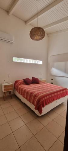 um quarto com uma cama grande e um cobertor vermelho em OMA CHILL HOUSE IGUAZU em Porto Iguaçu