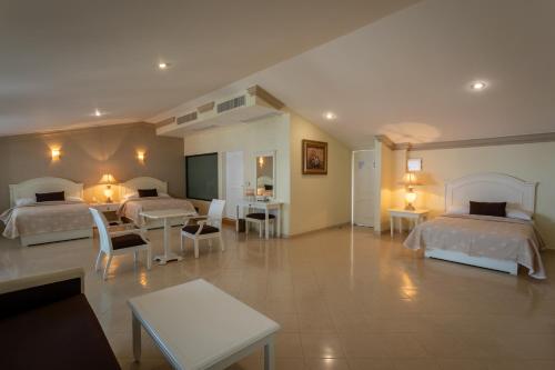 Habitación de hotel con 2 camas, mesas y sillas en Excelaris Grand Resort Conventions & Spa en Tequesquitengo