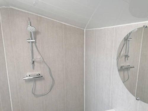 La salle de bains est pourvue d'une douche et d'un miroir rond. dans l'établissement La Cabane., à Magné