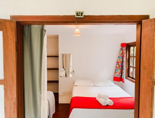 a bedroom with two beds and a red blanket at Pousada Zen Caraiva in Caraíva