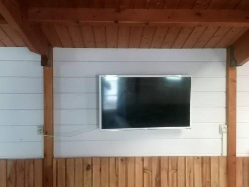 einen Flachbild-TV an einer weißen Wand in der Unterkunft La Cabane. in Magné