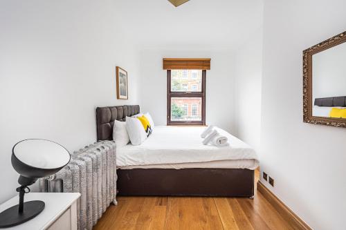 2 Bedroom Apartment by AV Stays Short Lets Southwark London With Free WiFi في لندن: غرفة نوم صغيرة مع سرير ومرآة