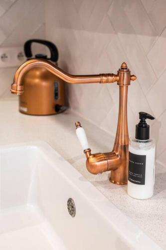 - un lavabo avec un robinet en or et une bouteille de savon dans l'établissement Luxuous loft in the jourdains'village-Imhost, à Paris