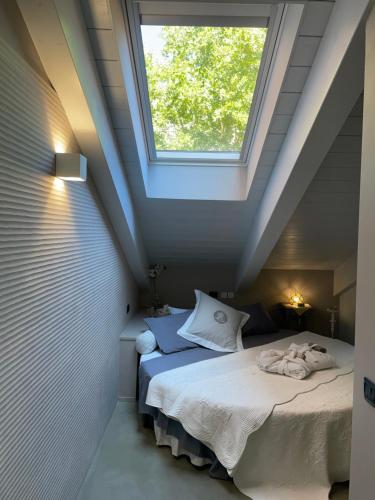 1 dormitorio en el ático con 1 cama con ventana en ACADAMIS - Suites & Junior Suites, en Turín