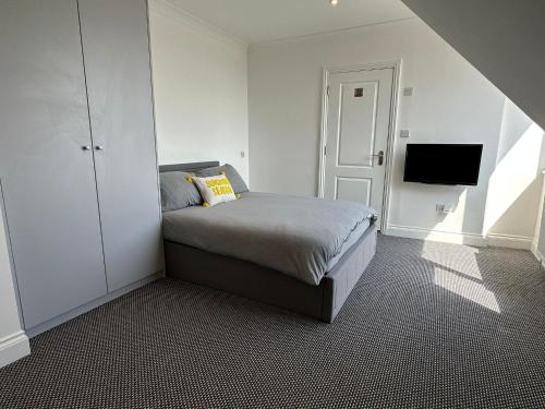 a bedroom with a bed and a tv on a wall at Stylish Modern, 1 Bed Flat, 15 Mins To Central London in Hendon