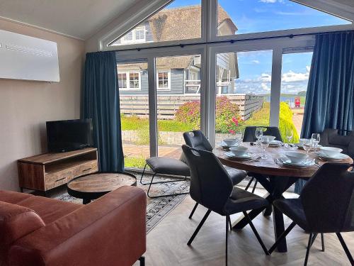 een woonkamer met een tafel en stoelen en een groot raam bij Waterpark Giethoorn in Giethoorn