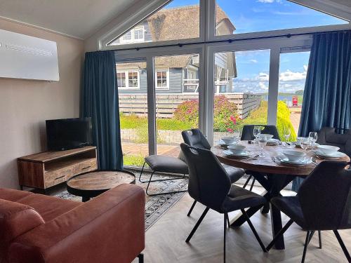 ein Wohnzimmer mit einem Tisch und Stühlen sowie einem großen Fenster in der Unterkunft Waterpark Giethoorn in Giethoorn