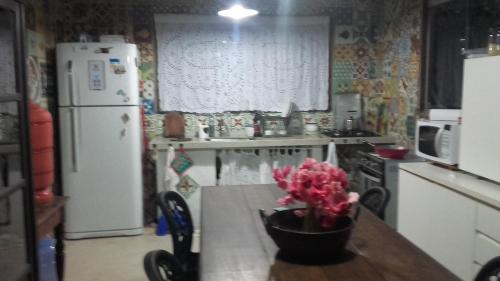 a kitchen with a table with a vase of flowers on it at CASA AMORA in São Miguel dos Milagres