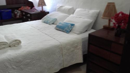 a bedroom with a white bed with pillows and a night stand at CASA AMORA in São Miguel dos Milagres
