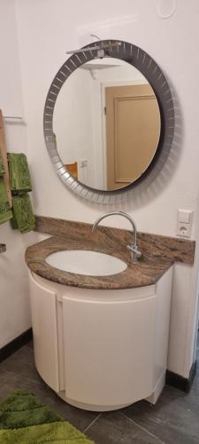un lavandino da bagno con sopra uno specchio circolare di Ferienwohnung am Kirchberg a Ettenheim
