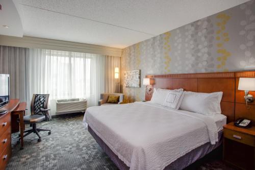 Habitación de hotel con cama, escritorio y TV. en Courtyard Republic Airport Long Island/Farmingdale en Farmingdale
