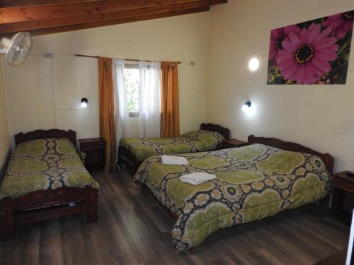 1 dormitorio con 2 camas y un dibujo floral en la pared en Los Girasoles team family en El Bolsón