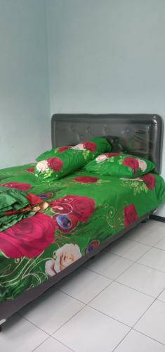 ein Bett mit einer grünen Decke mit Blumen drauf in der Unterkunft Dedwa Homestay syariah in Batu