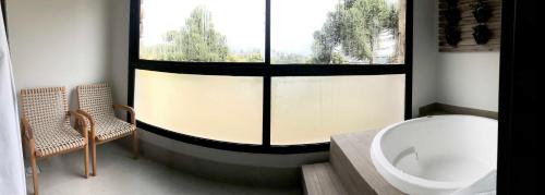 a bathroom with a large window and a tub and a sink at Quarto no Wanderlust Experience Hotel in Campos do Jordão