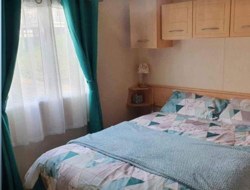 1 dormitorio con 1 cama con edredón azul y ventana en Loch Earn Holiday Home, en St Fillans