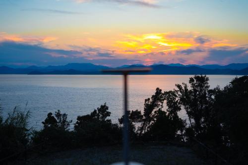a sunset over a body of water with a pole at sauna×star×sea　Highland Panorama Ocean View in Shima