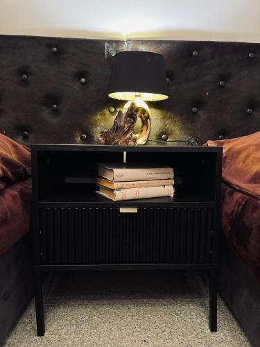 a bed with a table with books and a lamp at Catherine's house in Veľký Krtíš