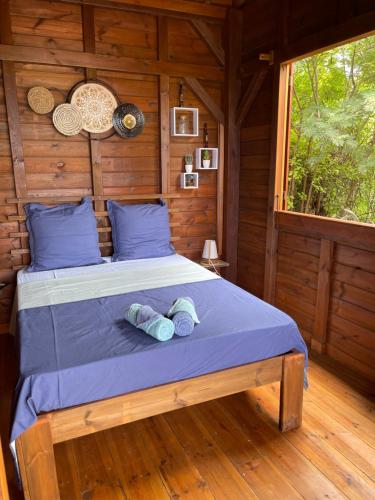 łóżko w drewnianym pokoju z dwoma rękawicami w obiekcie Bungalow Lanar'am Graj - 2 w mieście Bouillante