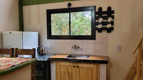 une cuisine avec un évier et une fenêtre dans l'établissement Minicasa Rural Maria Preta, à Puerto Iguazú