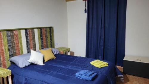 Un dormitorio con una cama azul con sábanas azules y almohadas amarillas. en Minicasa Rural Maria Preta en Puerto Iguazú
