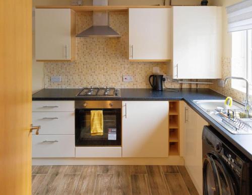 a kitchen with white cabinets and a stove top oven at Stylish 3 Bedroom and free parking in Thamesmead