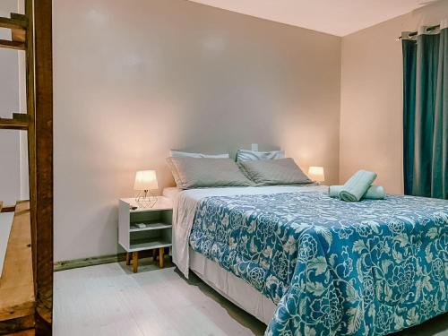 a bedroom with a bed with a blue comforter and a table at Garden 437 Suítes in Florianópolis