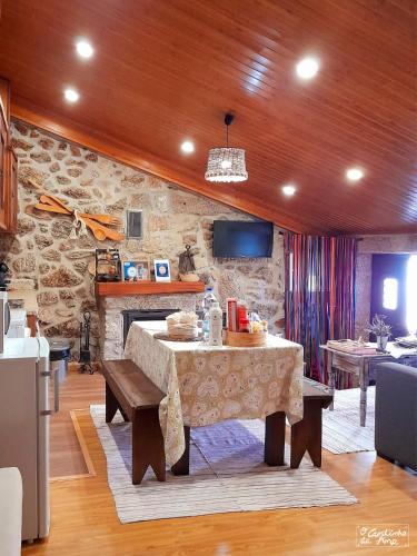 a living room with a table and a stone wall at O Cantinho da Ana in Sortelha