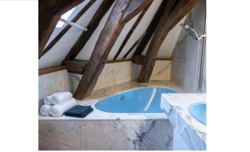 - une salle de bains mansardée pourvue d'une baignoire bleue dans l'établissement Suite Toussaint - Calme & Authentique, à Angers
