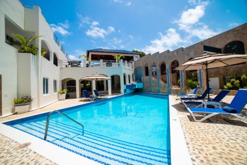einen Pool mit Stühlen und Sonnenschirmen neben einem Haus in der Unterkunft High Life Resort & Spa in Struie