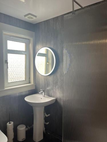 a bathroom with a sink and a mirror at Loch Lomond Apartment in Alexandria