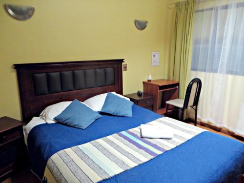 a bedroom with a blue and white bed and a desk at Hostal Remember in Temuco