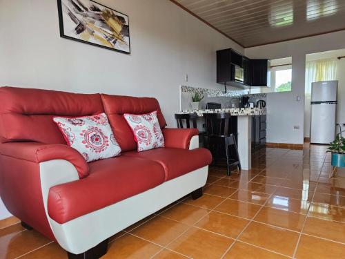 a red couch in a living room with a kitchen at Volcano View Apartment in Fortuna