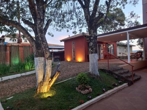 una casa con dos árboles en un patio en Pousada Cantares, en Tiradentes